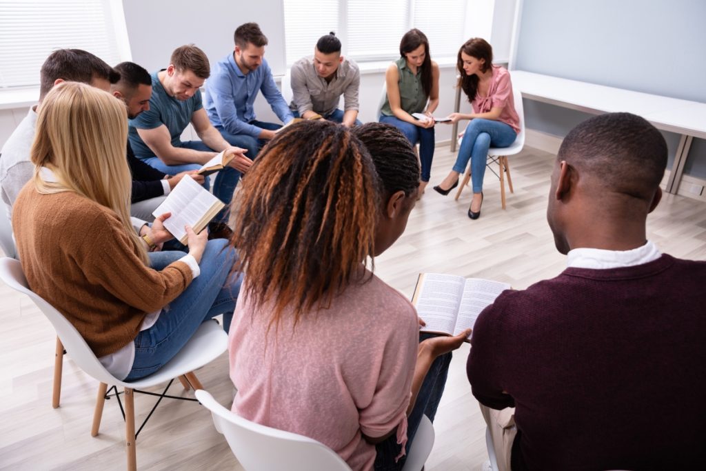 group of young multi ethnic people reading holy bible together